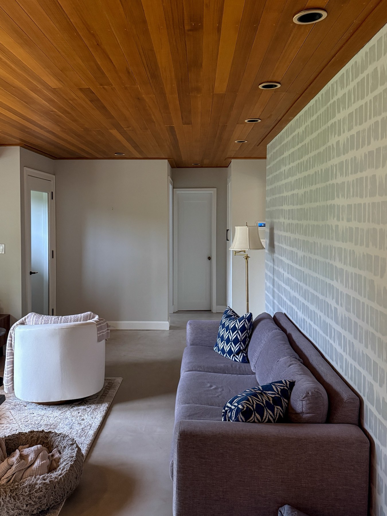Remodeled living room with wood plank ceiling and accent wallpaper wall