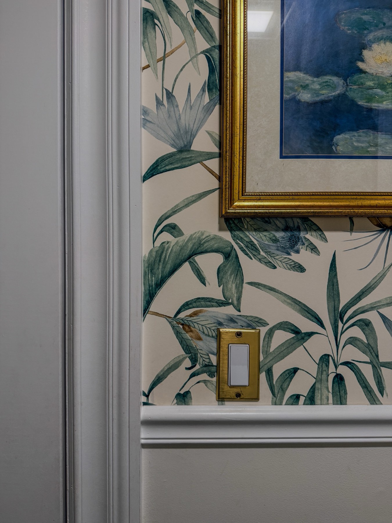 Detail of botanical wallpaper and gilded framed art in a remodeled home